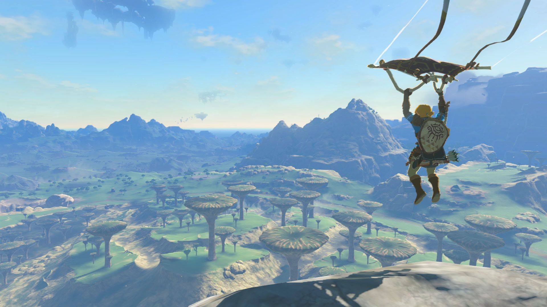  A character uses a glider to soar over a lush landscape filled with mushroom-like trees and distant mountains under a clear blue sky.