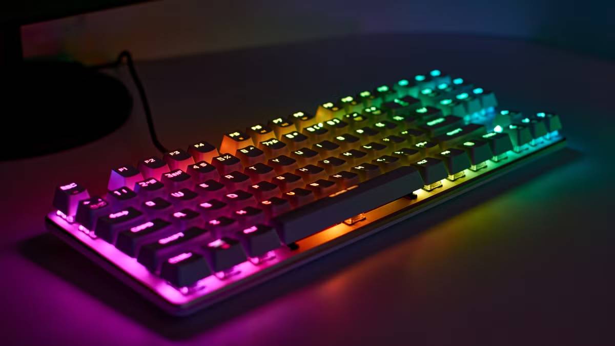  A vibrant, backlit mechanical keyboard displaying a gradient of rainbow colors across its keys, set against a dark background.