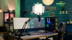 A modern gaming setup featuring dual monitors, a microphone on an arm, gaming keyboard, and colorful PC case in a stylish room.