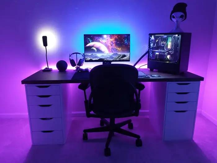 A modern gaming desk with a computer, colorful LED lights, and a stylish chair, creating an inviting tech workspace.