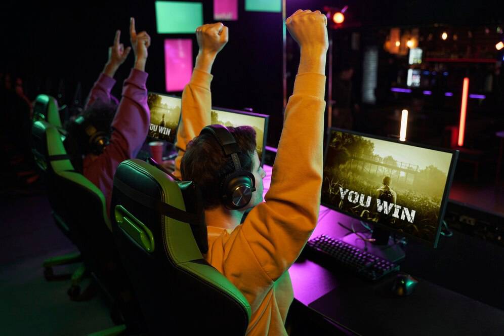  Two gamers celebrating victory with raised arms, headsets on, as 