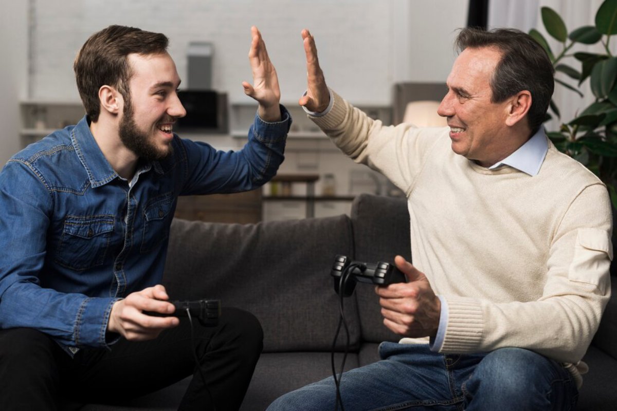Two men, young and older, high-fiving while playing video games in a cozy living room.