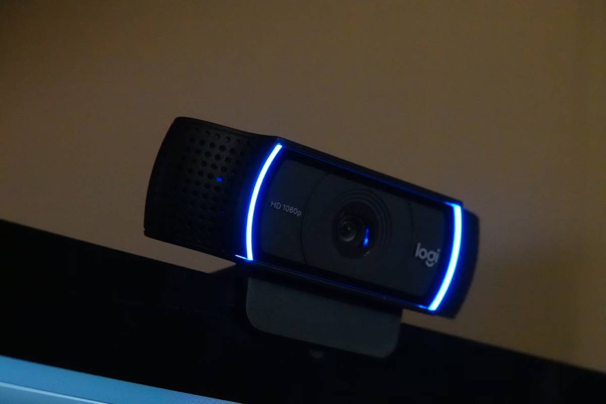 A webcam with blue LED lights mounted on top of a computer monitor in a dimly lit room.