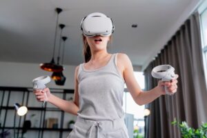 Young woman using virtual reality headset and controllers indoors, appearing engaged and astonished.